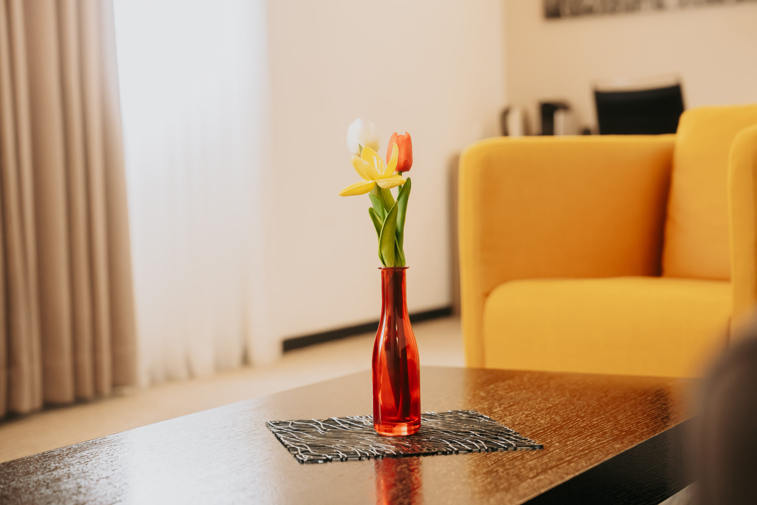 Tulpe in roter Vase vor gelbem Sessel