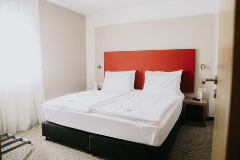 Doppelzimmer mit Boxspringbett und rotem Kopfteil