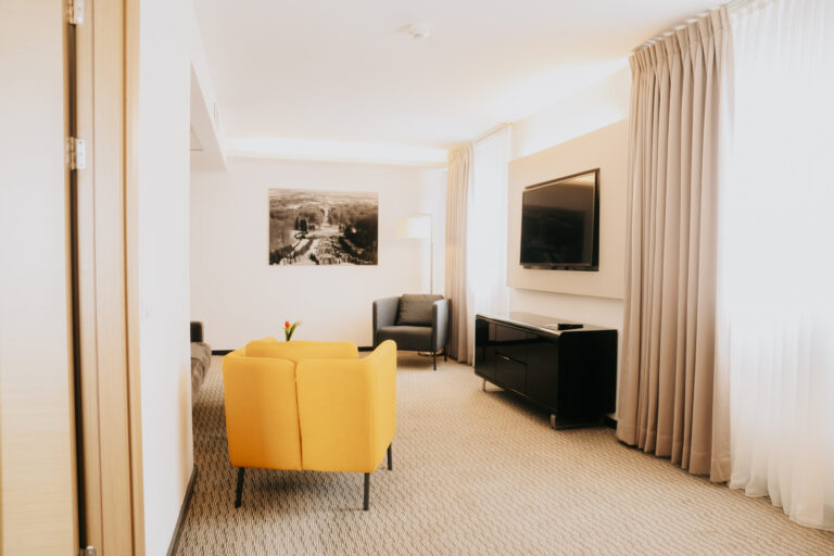 Wohnbereich einer Suite mit gelbem Sessel und Sofa